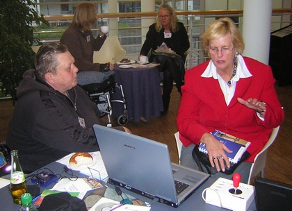 Marianne Ziegler und Angelika Gemkow sitzen vor einem Computer und Frau Gemkow sieht sich die Hilfsmittel an.