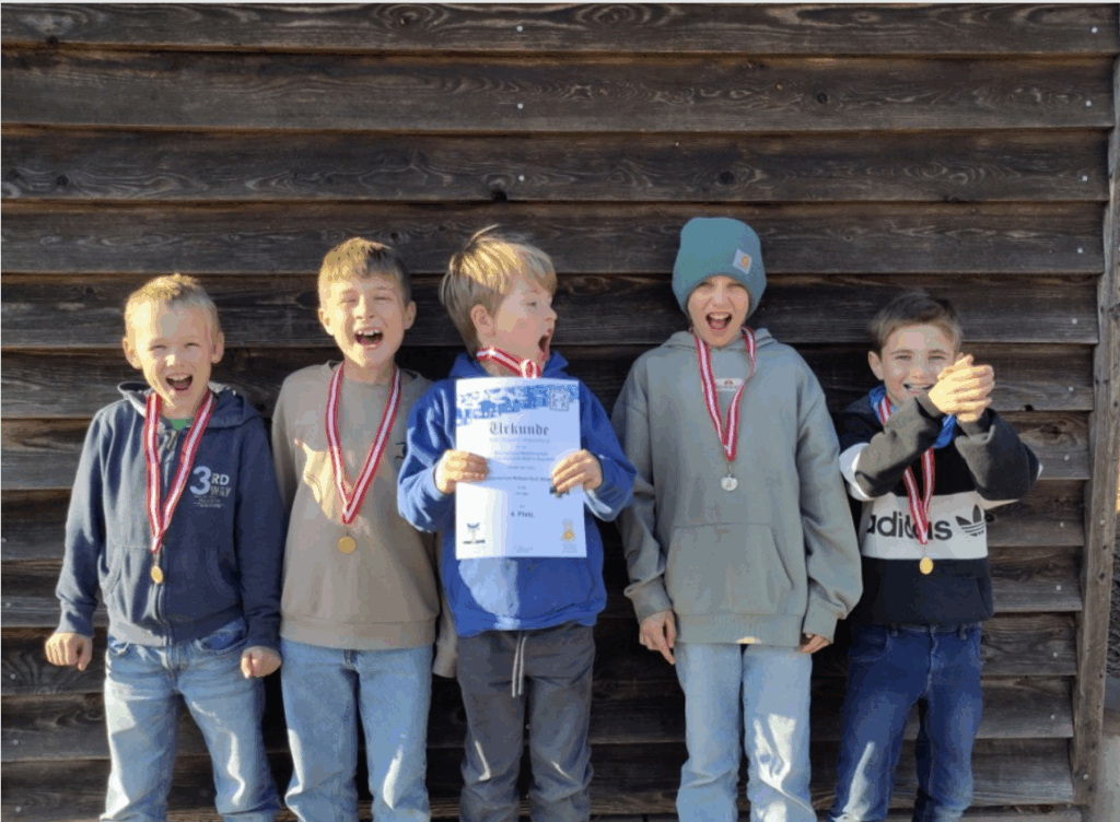 Fünf Kinder freuen sich lachend über ihre Aufzeichnungen und zeigen eine Urkunde.