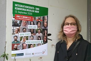 Moderatorin Uschi Heeke vor dem Plakat, das auch zur Wahl des Integrationsrats am 13.9. aufruft. (Foto: Ralf Clausen)